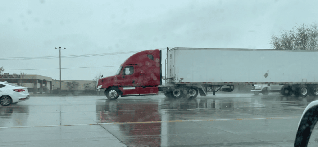 Red semitruck on the road in the rain