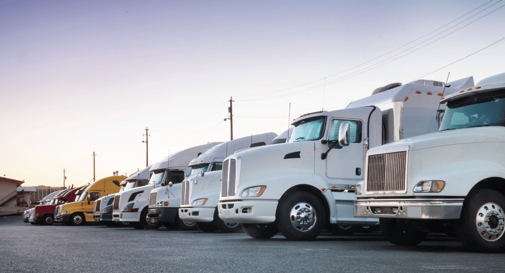 A line of semi trucks parked in a truck stop parking lot.