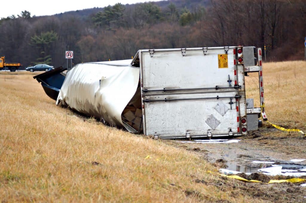 A tractor trailer on its side in the median after a roll over accident.