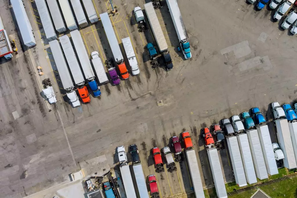 Top aerial view car parking for heavy trucks stop on rest area in the highway trucks stand in a row