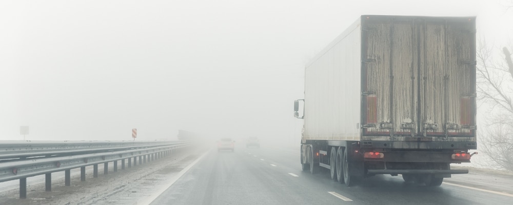 A truck driving down a highway in the rain.